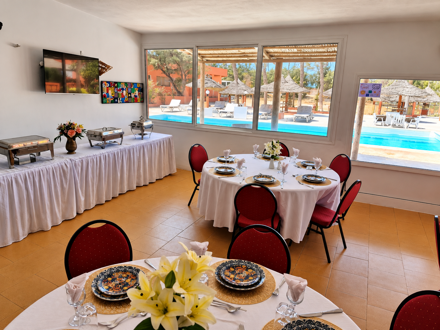 La salle réelle du restaurant de l’Hôtel Dior : tables rondes dressées, chaises bordeaux, buffet et vue sur la piscine