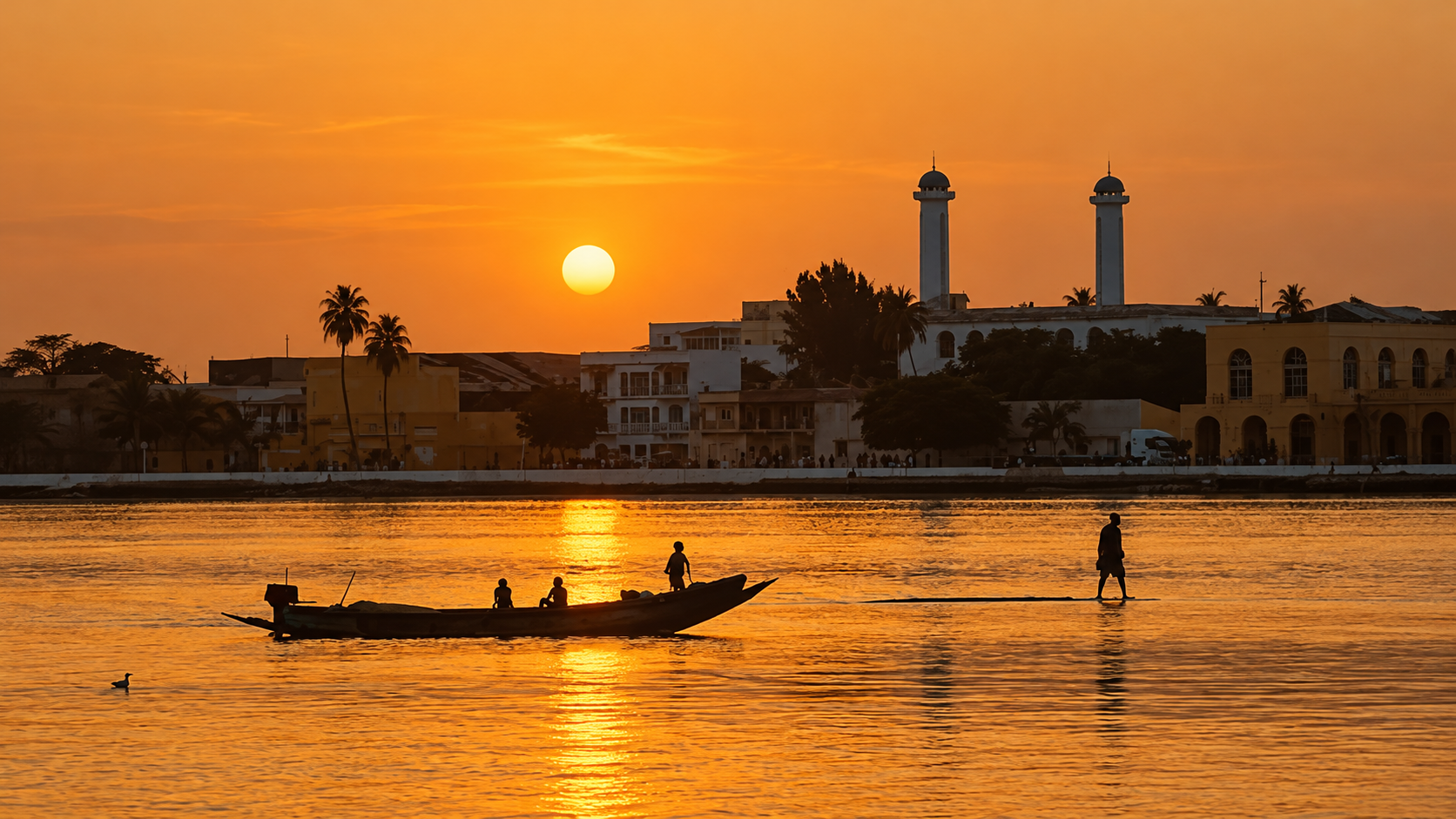Coucher de soleil sur Saint-Louis, avec les deux minarets, la pirogue et les silhouettes sur le fleuve